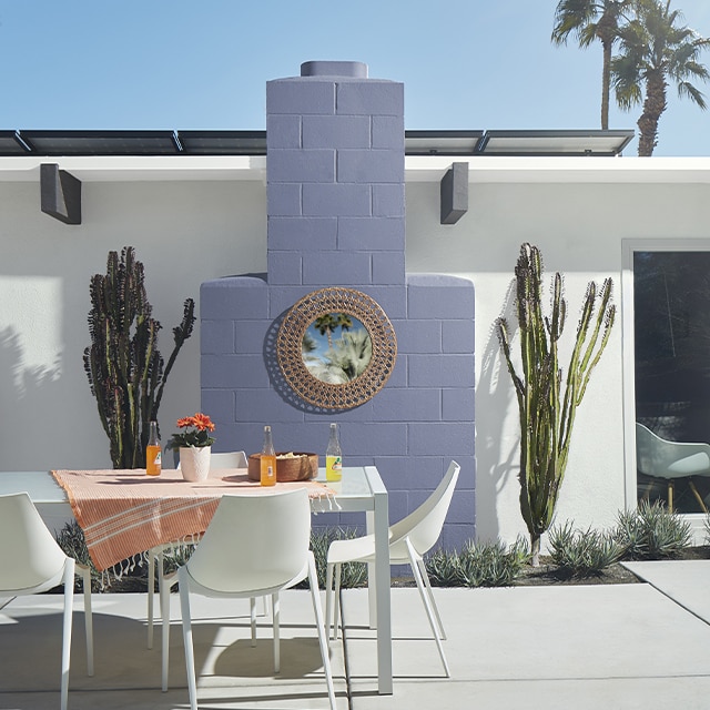 Voici une maison en stucco blanc dont la cheminée extérieure lilas flanquée de deux cactus agrémente le coin à manger au mobilier blanc de ce patio. Voici une maison en stucco blanc dont la cheminée extérieure lilas flanquée de deux cactus agrémente le coin à manger au mobilier blanc de ce patio.