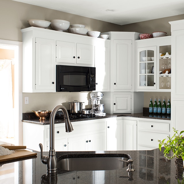 The same kitchen after a makeover, with fresh white-painted cabinets, black countertops and appliances. The same kitchen after a makeover, with fresh white-painted cabinets, black countertops and appliances.