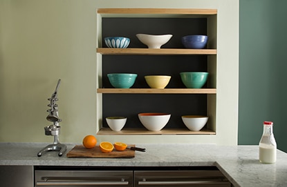 Monochromatic kitchen walls with shades of dark and light green including three inset shelves holding 9 bowls. Monochromatic kitchen walls with shades of dark and light green including three inset shelves holding 9 bowls.