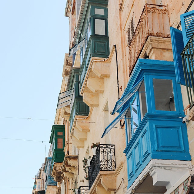 Un immeuble beige avec des balcons fermés aux nuances de bleu et de vert. Un immeuble beige avec des balcons fermés aux nuances de bleu et de vert.