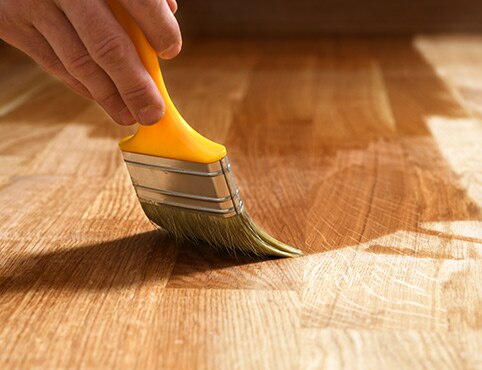 Un peintre professionnel applique la finition à un parquet de bois franc. Un peintre professionnel applique la finition à un parquet de bois franc.